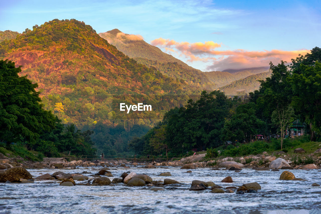 Scenic view of river by mountains against sky
