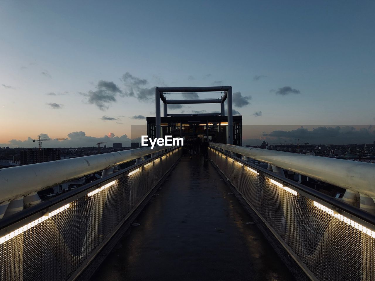 FOOTBRIDGE OVER ILLUMINATED BRIDGE AT SUNSET