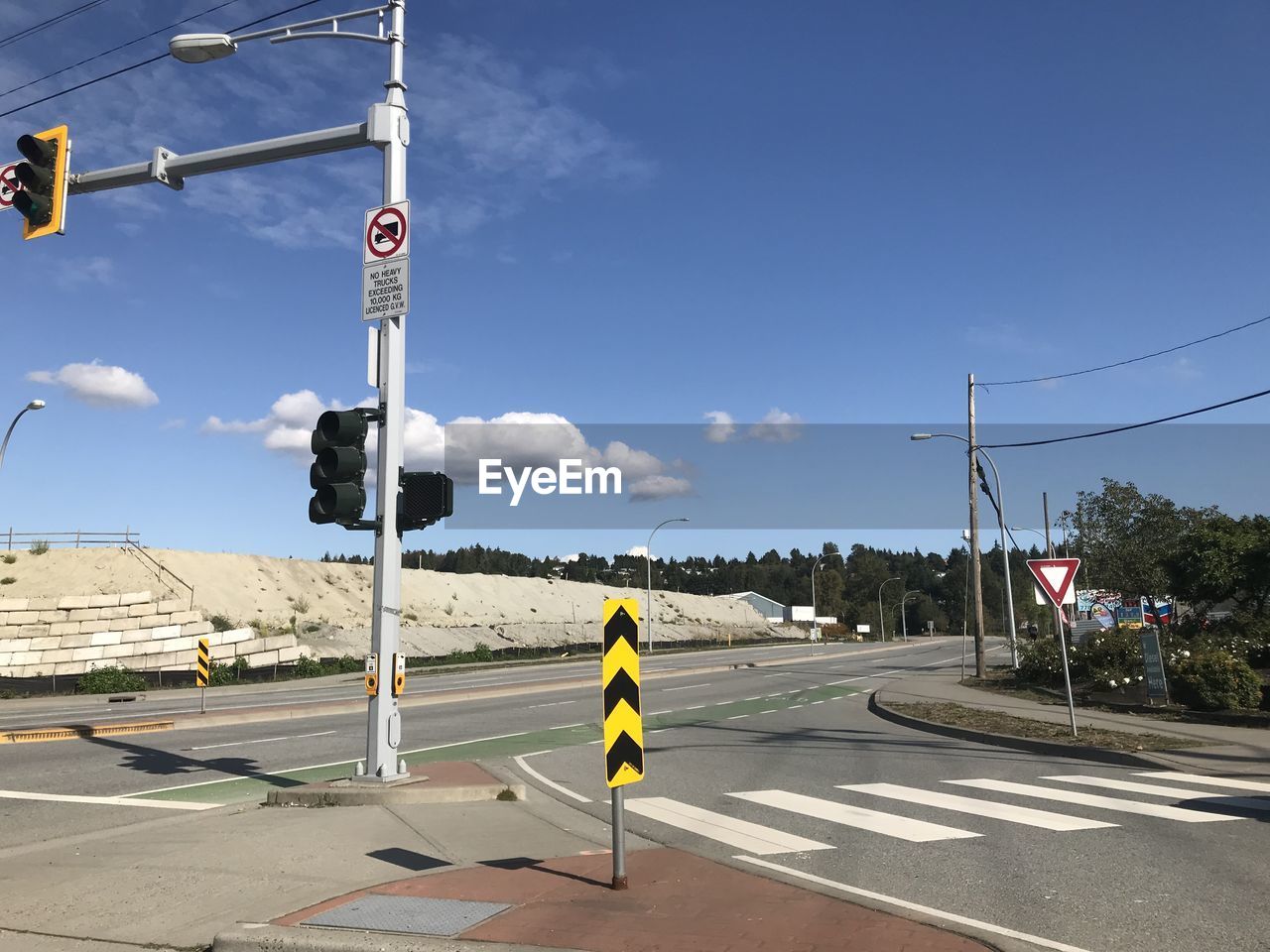 Road sign on street against sky