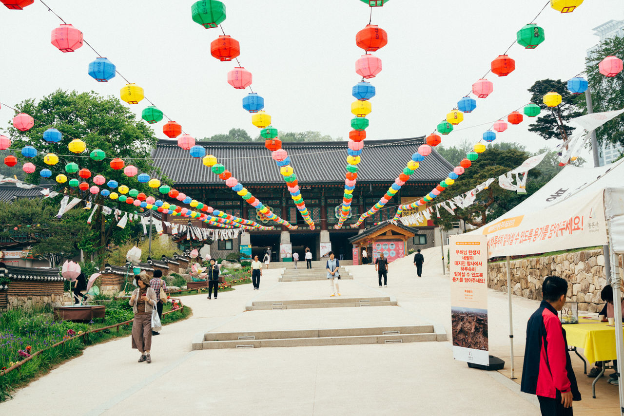 People walking below colorful lanterns decorated at bongeunsa temple