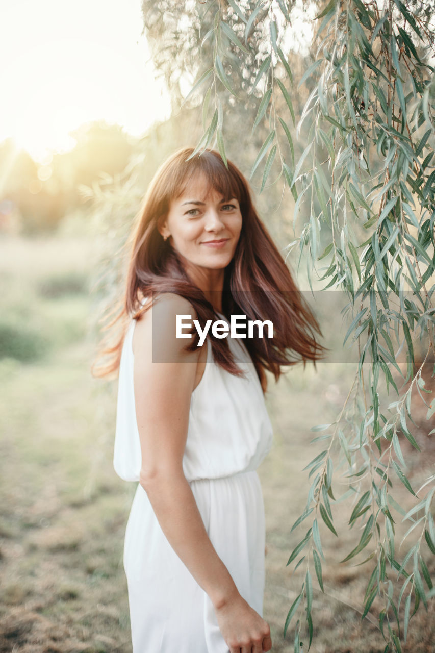 Portrait of smiling woman by tree