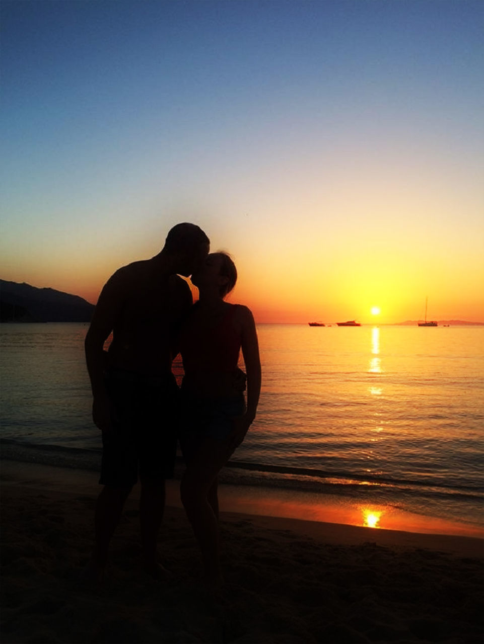 Silhouette of couplte kissing on beach at sunset