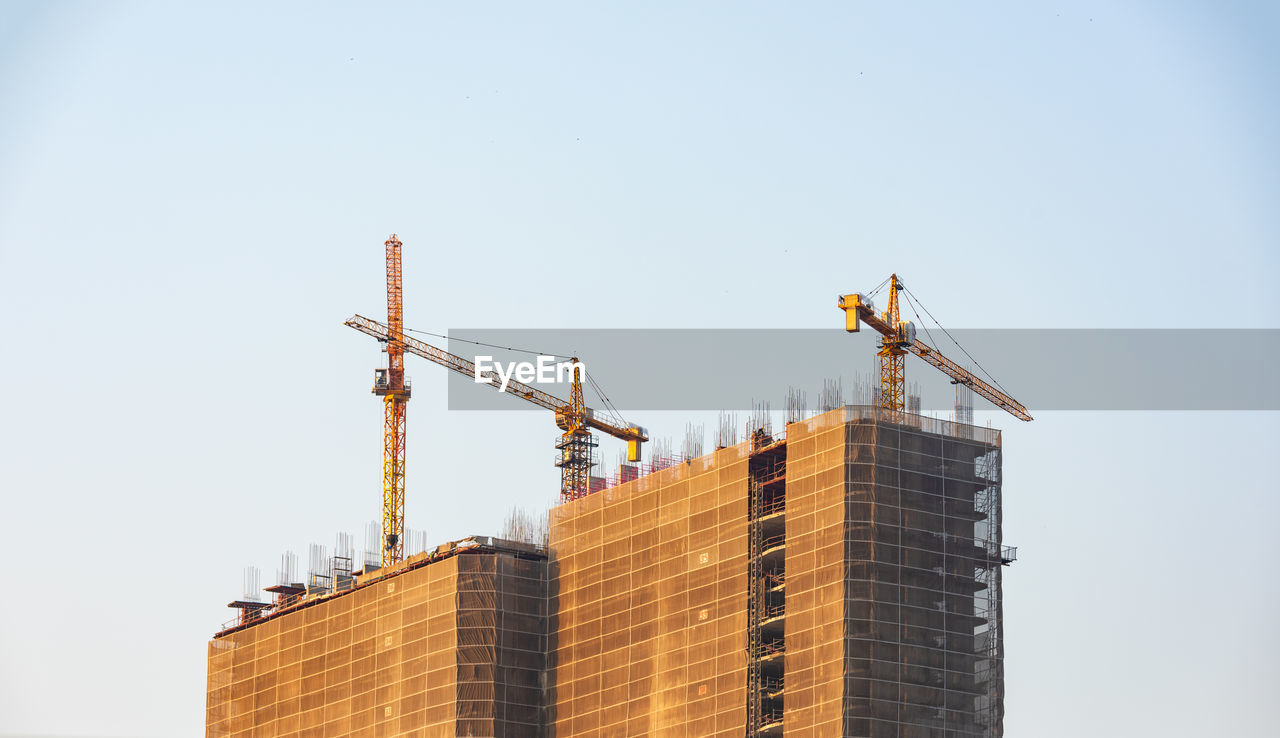 LOW ANGLE VIEW OF CRANE AGAINST BUILDING