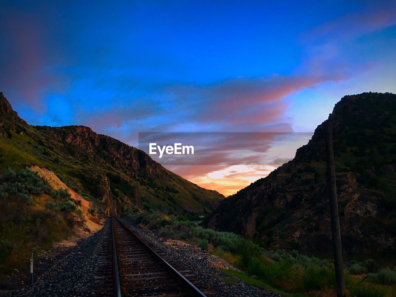 VIEW OF RAILROAD TRACK AGAINST SKY DURING SUNSET