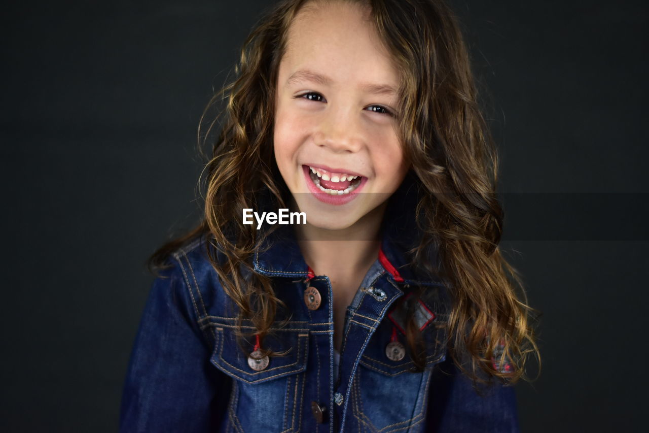 Portrait of smiling girl against black background