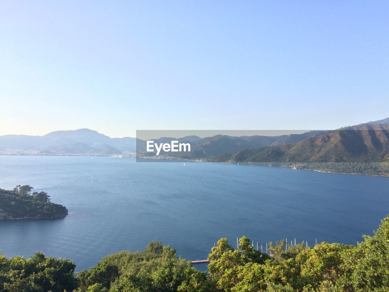 Scenic view of lake and mountains against clear blue sky