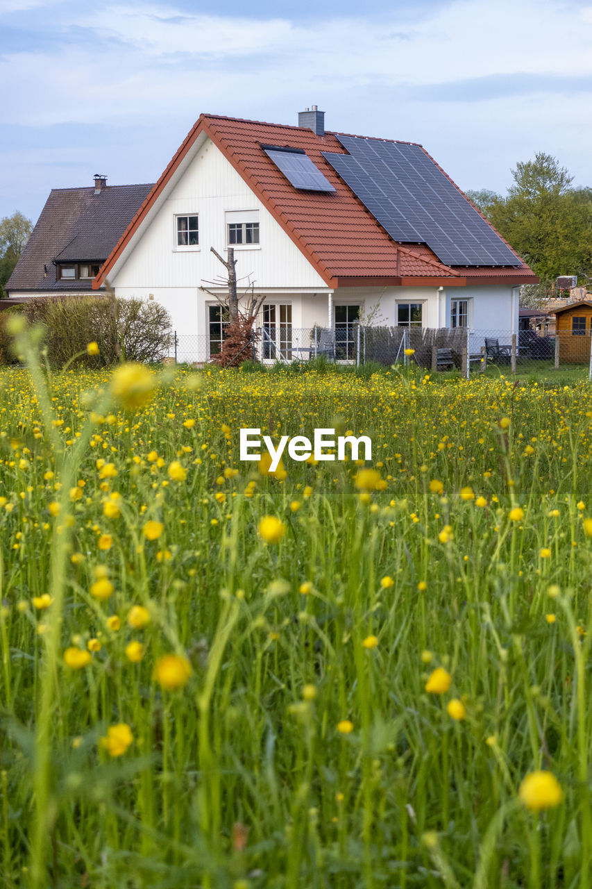 Solar panels on roof of house by meadow