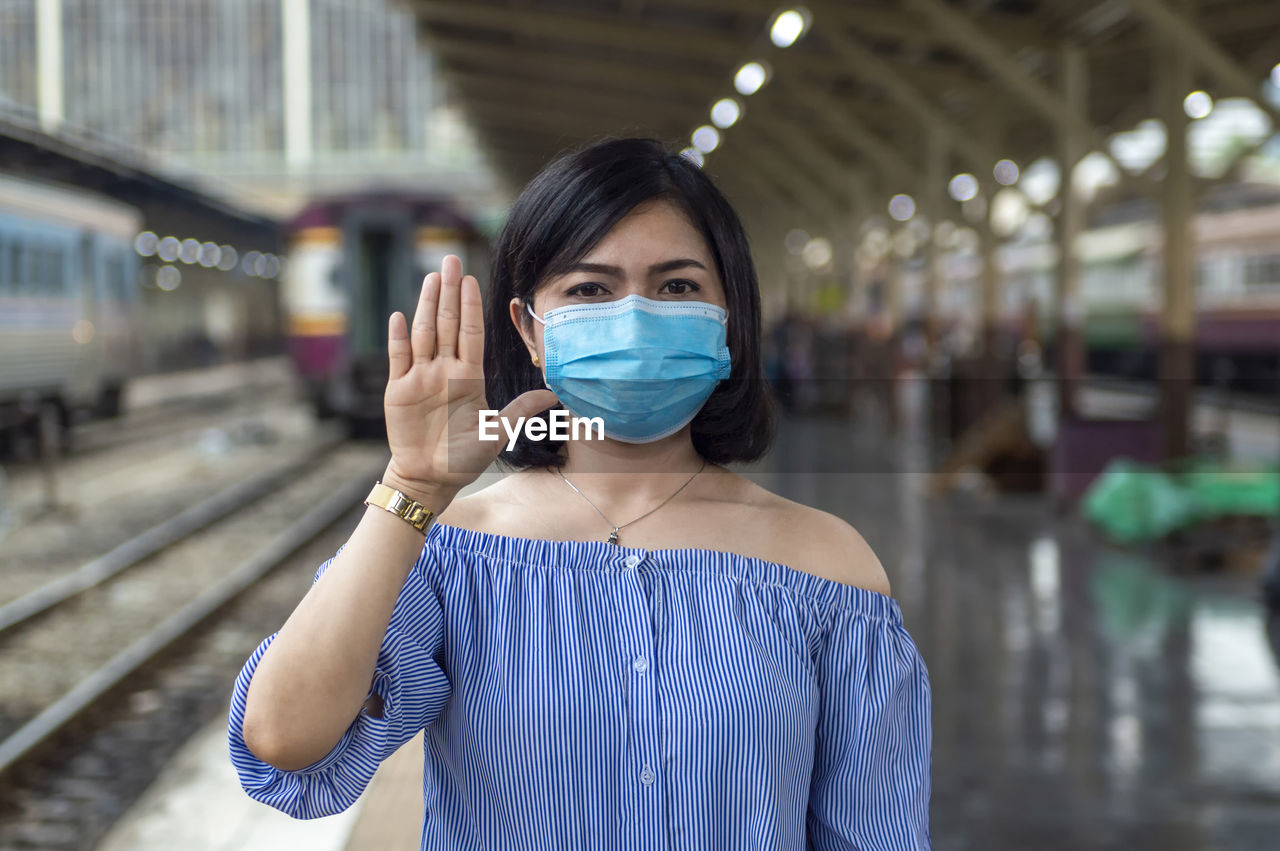 Portrait of young woman wearing mask standing on railway station
