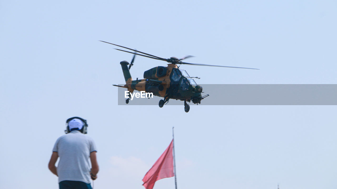 air vehicle, helicopter, transportation, flying, sky, mode of transportation, aircraft, vehicle, aviation, nature, air force, airplane, military, men, mid-air, propeller, day, motion, rear view, clear sky, adult, government, two people, on the move, rotorcraft, person, blue, outdoors, military helicopter, occupation