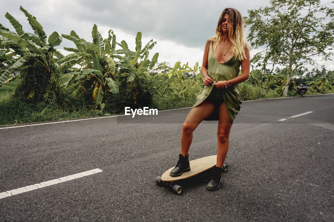 Young woman on skateboard against sky