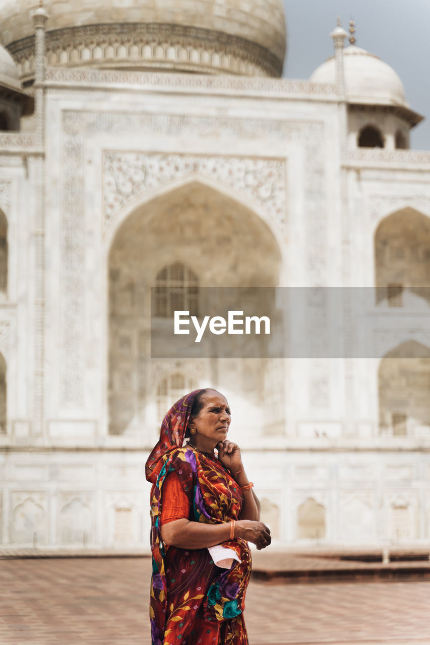 YOUNG WOMAN STANDING AGAINST A TEMPLE