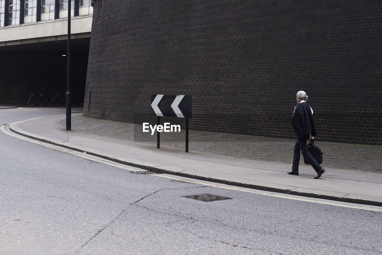 Senior businessman with luggage walking on pavement