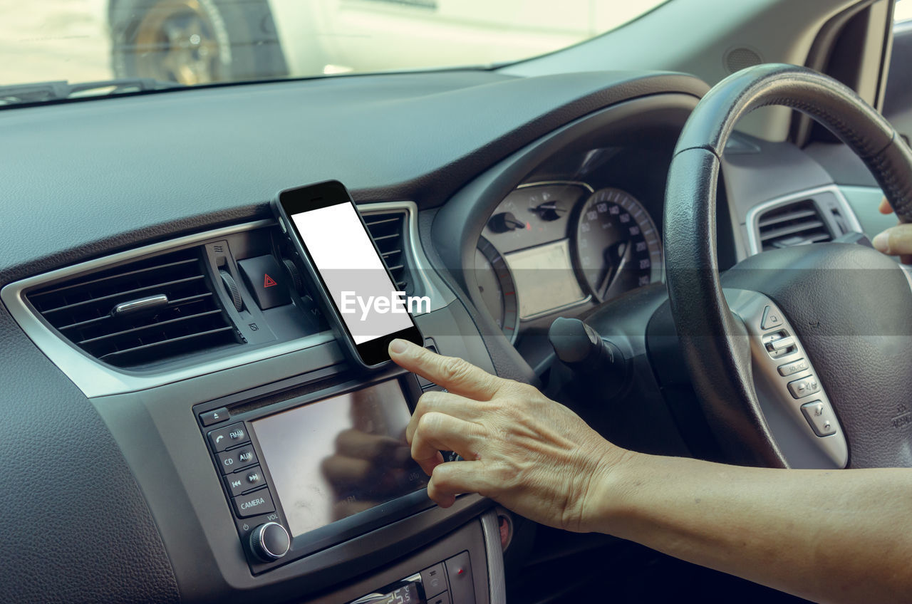 Cropped image of woman using smartphone while driving car on road