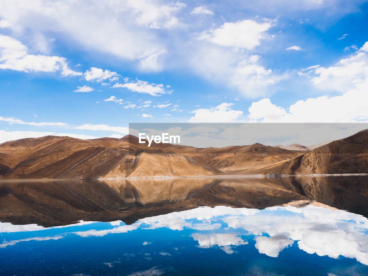 Scenic view of lake by mountains against sky