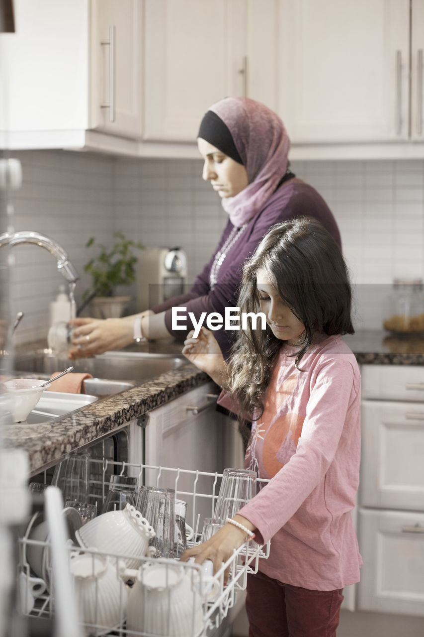 Girl helping mother in kitchen