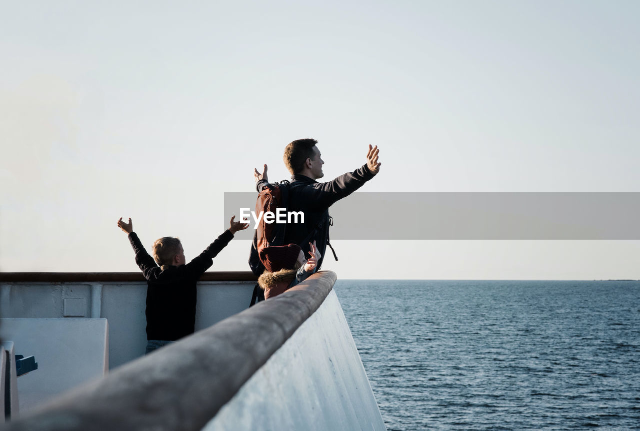 Father and his children playing titanic feeling the breeze on a boat