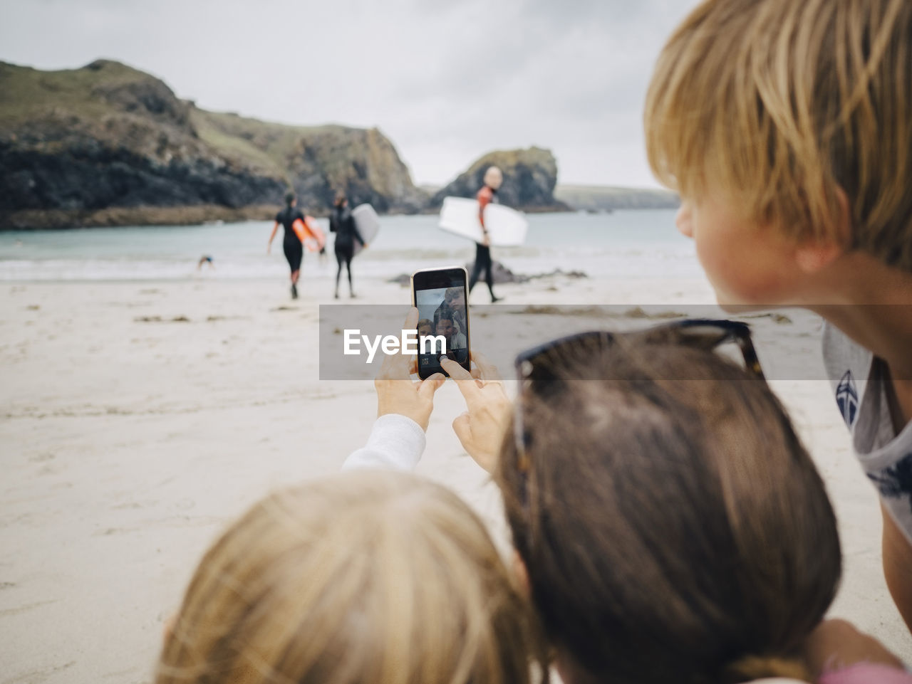 Woman taking selfie with kids from mobile phone at beach