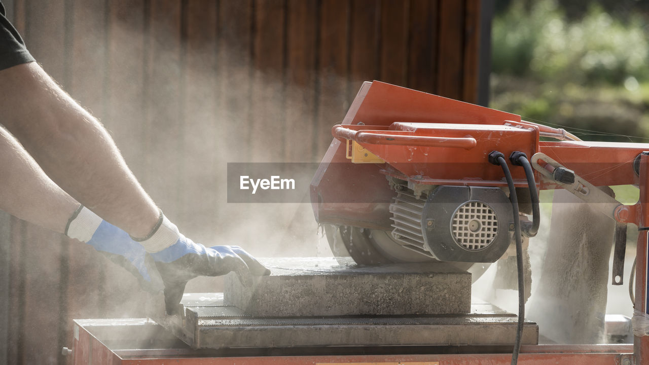 REAR VIEW OF MAN WORKING ON MACHINE PART