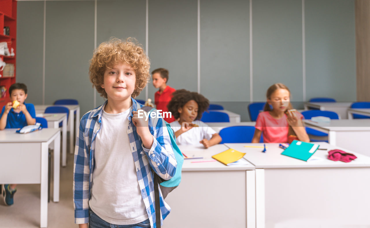 Portrait of cute boy standing in classroom