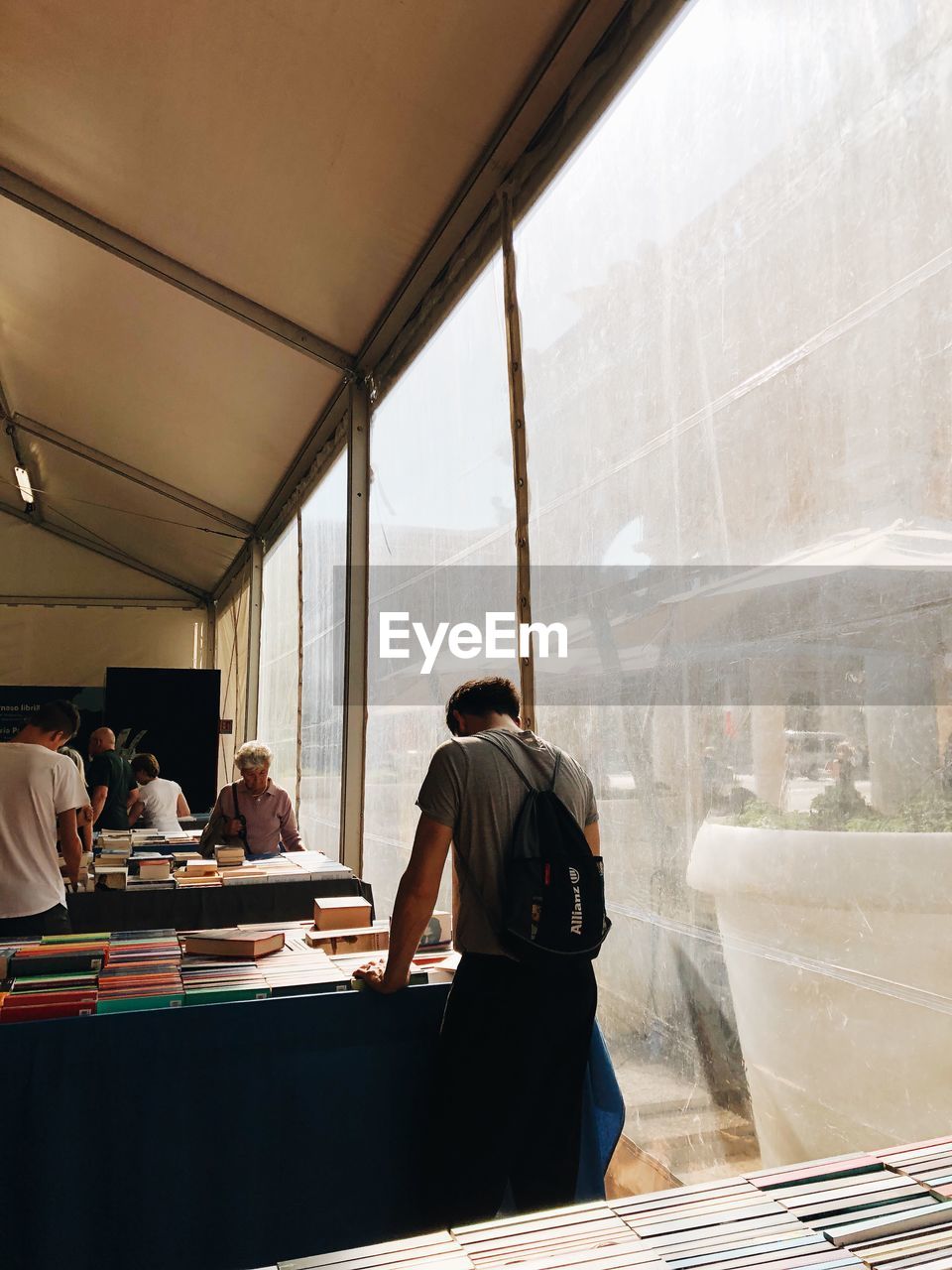 Group of people looking at books collection on tables by windows