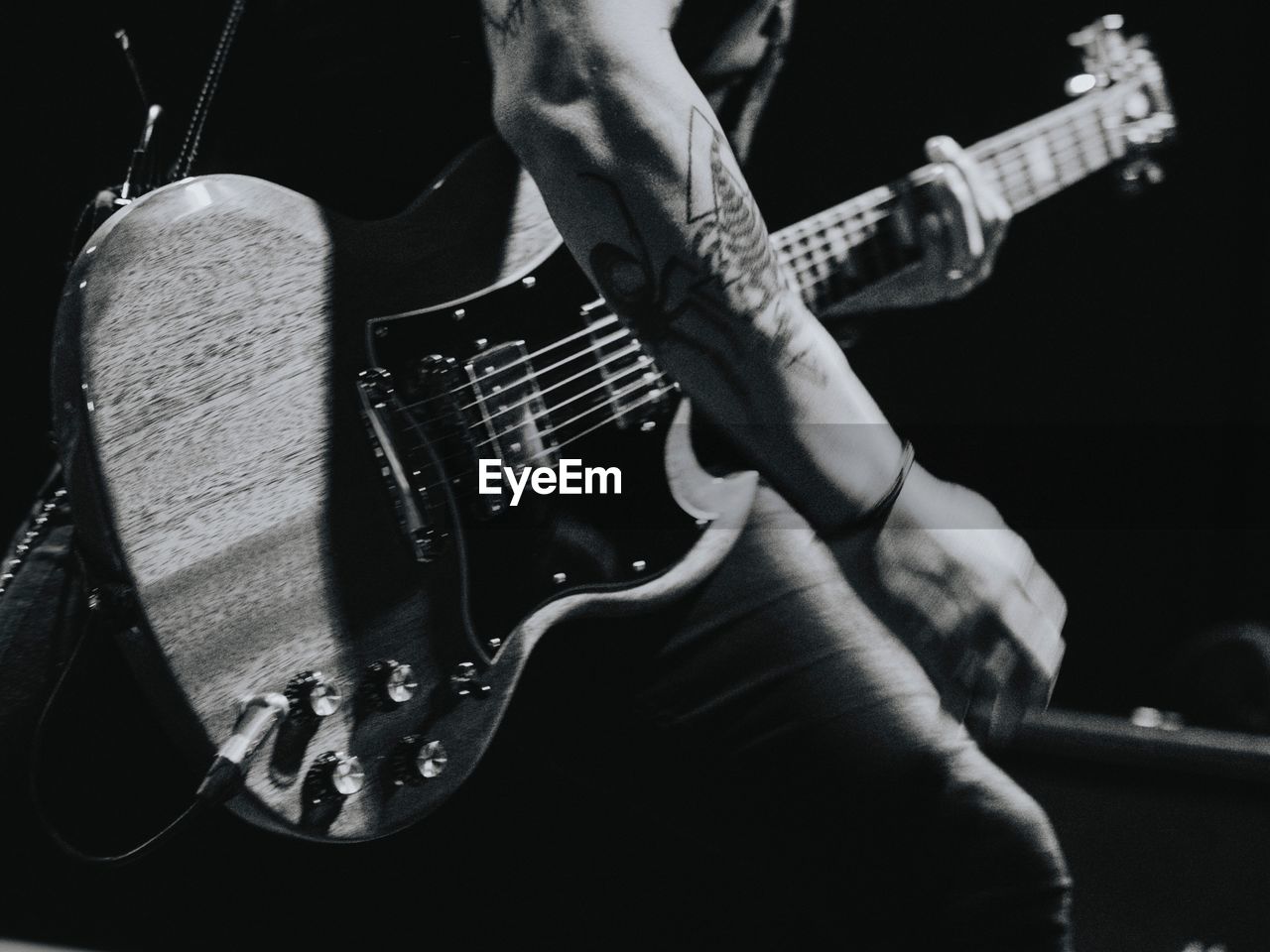 MIDSECTION OF MAN PLAYING GUITAR AT NIGHTCLUB