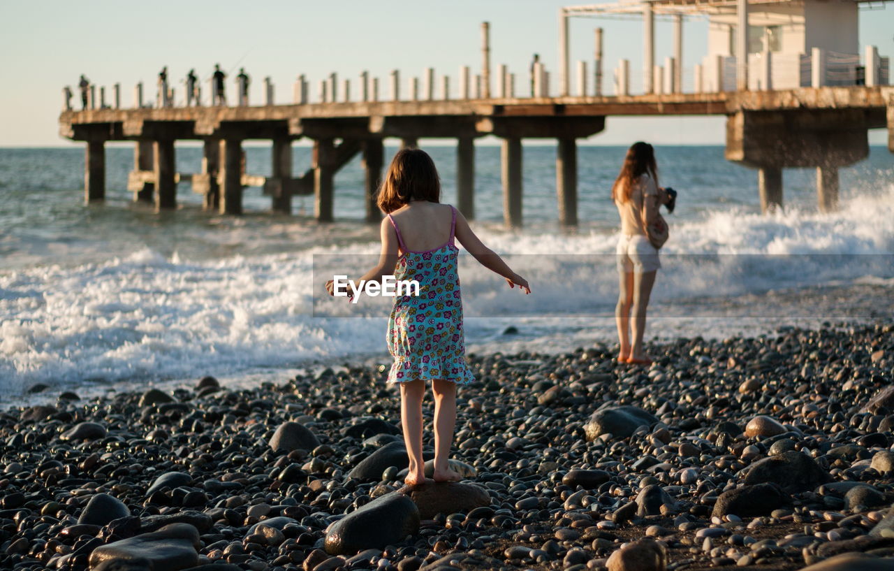 Mother with child girl at the sea beach on sunset