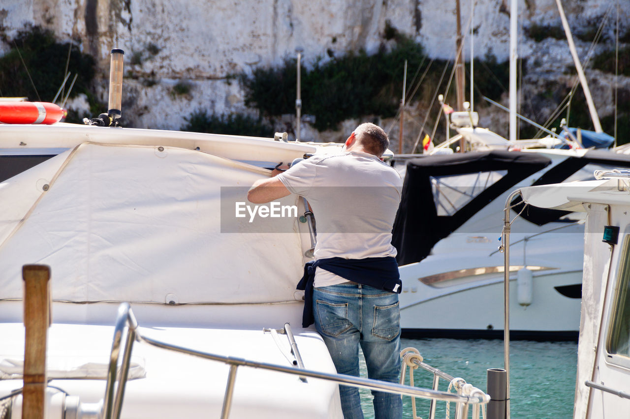 REAR VIEW OF MAN WORKING IN BOAT