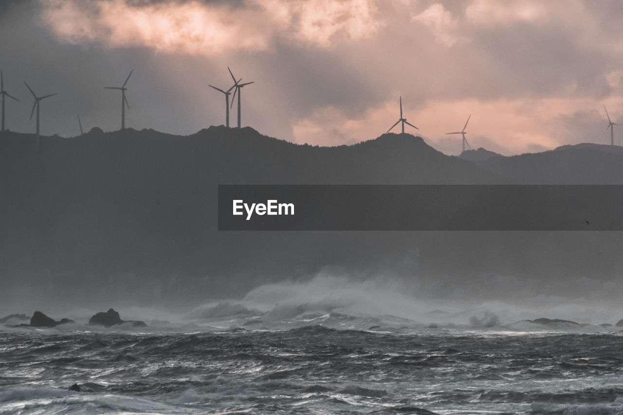 Big waves break on the coast, in the sunlit sea, passing through the clouds . galicia, spain.