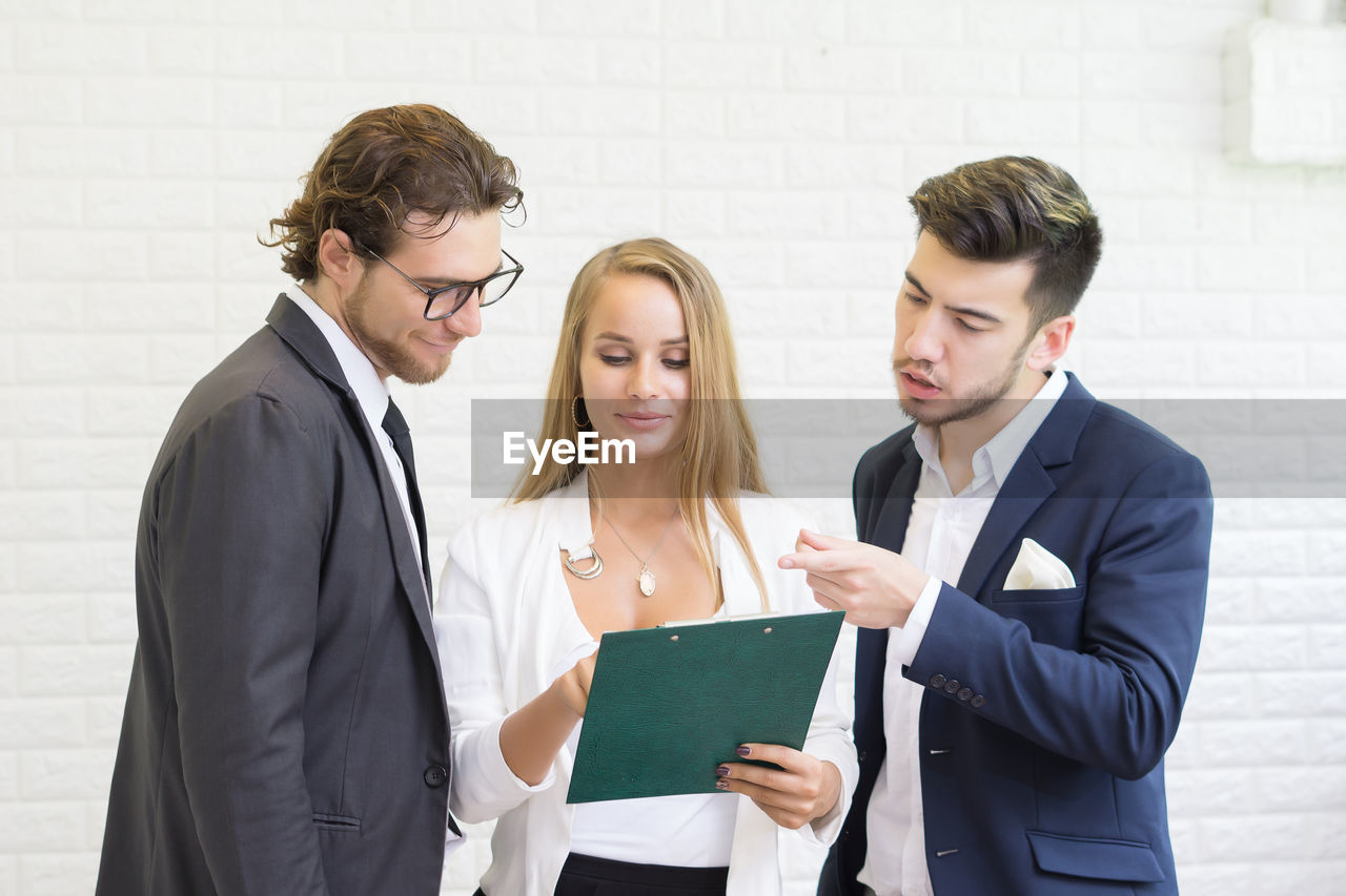 Business colleagues discussing over document while standing in office