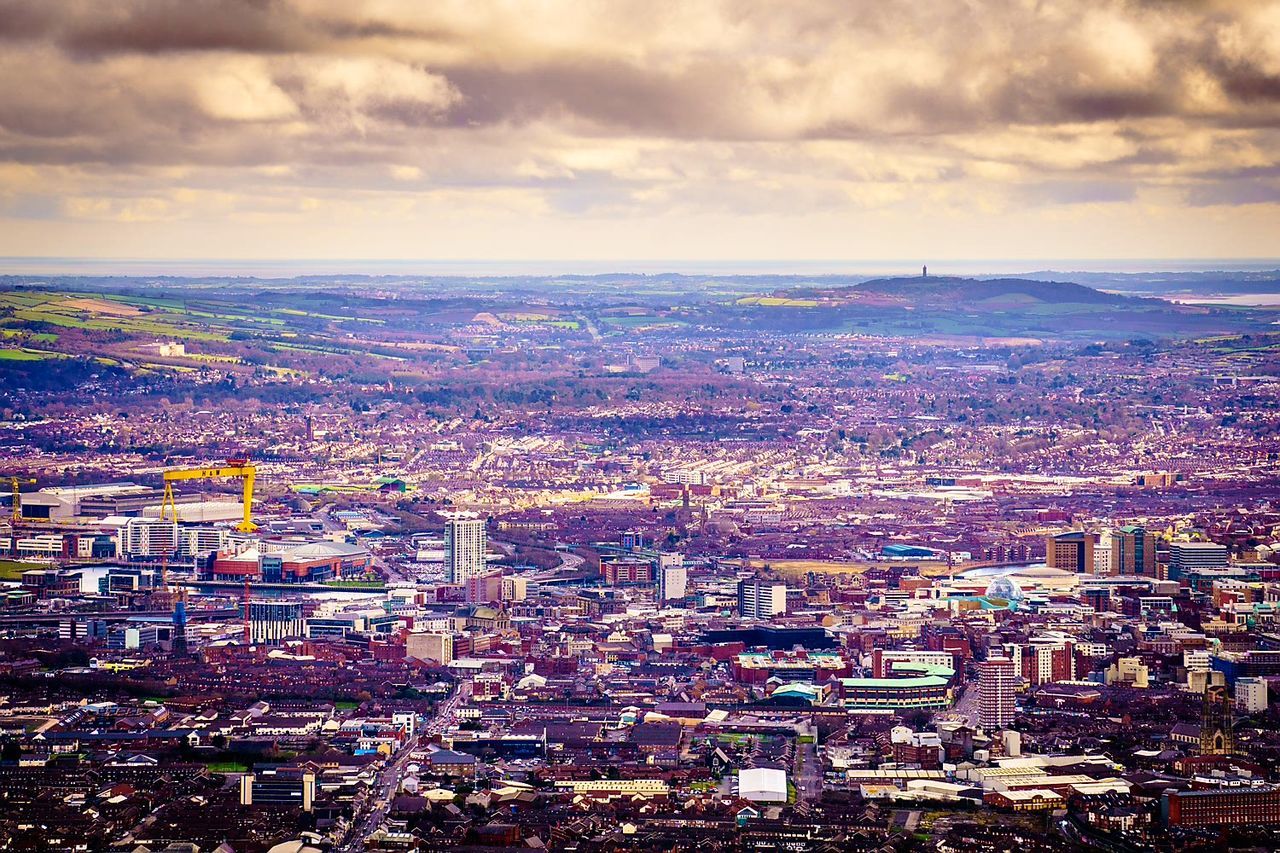 Aerial view of cityscape against cloudy sky