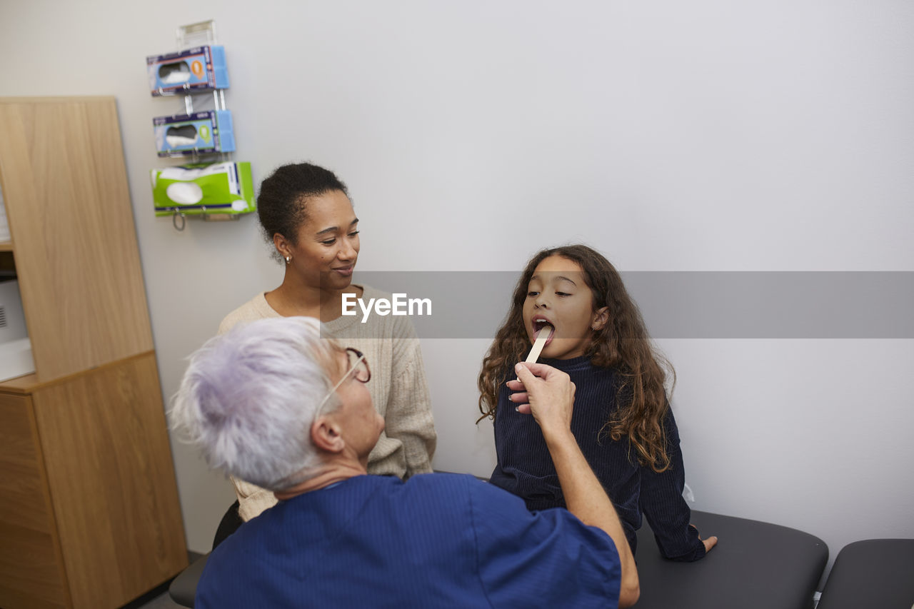 Female doctor checking girls throat