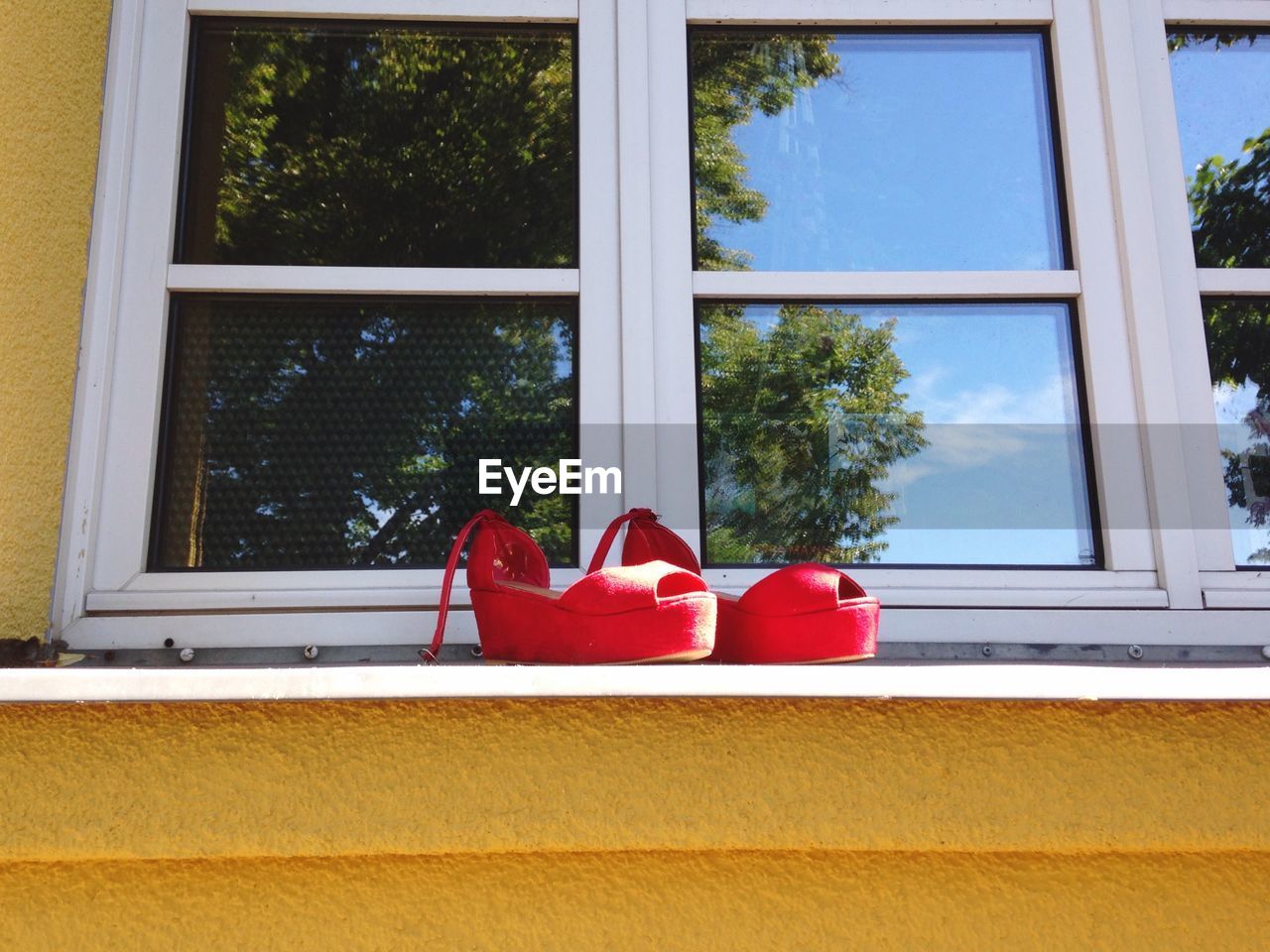 Red shoes on window sill of house during sunny day