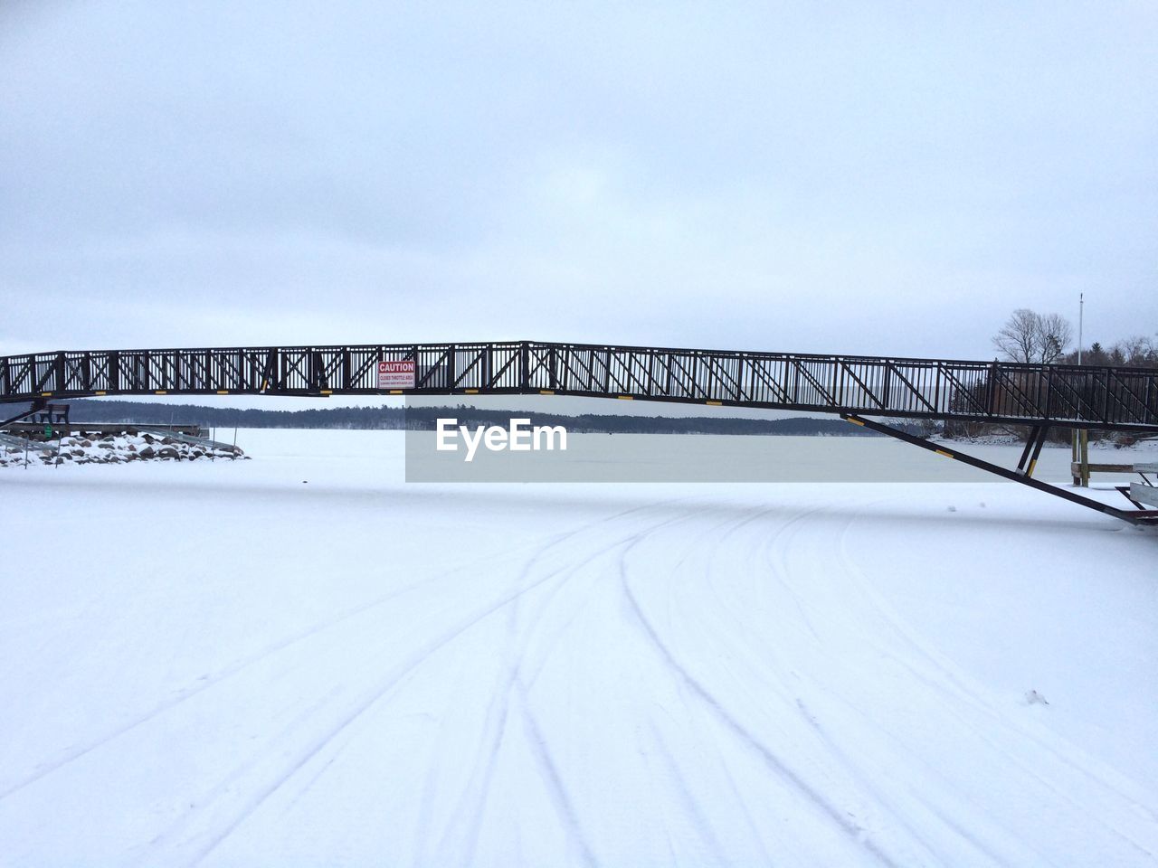 Footbridge over snow covered field during winter