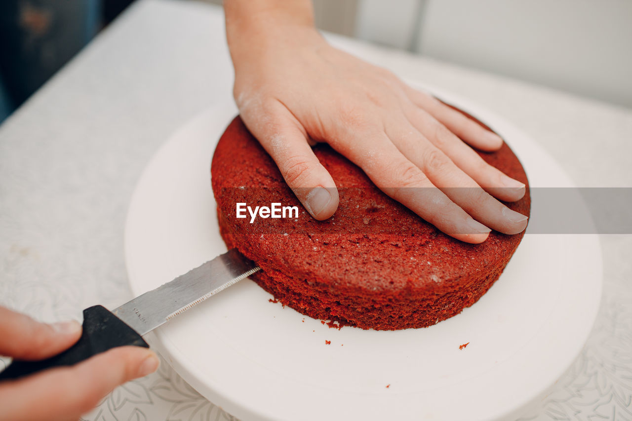 Woman cutting red velvet cake on table