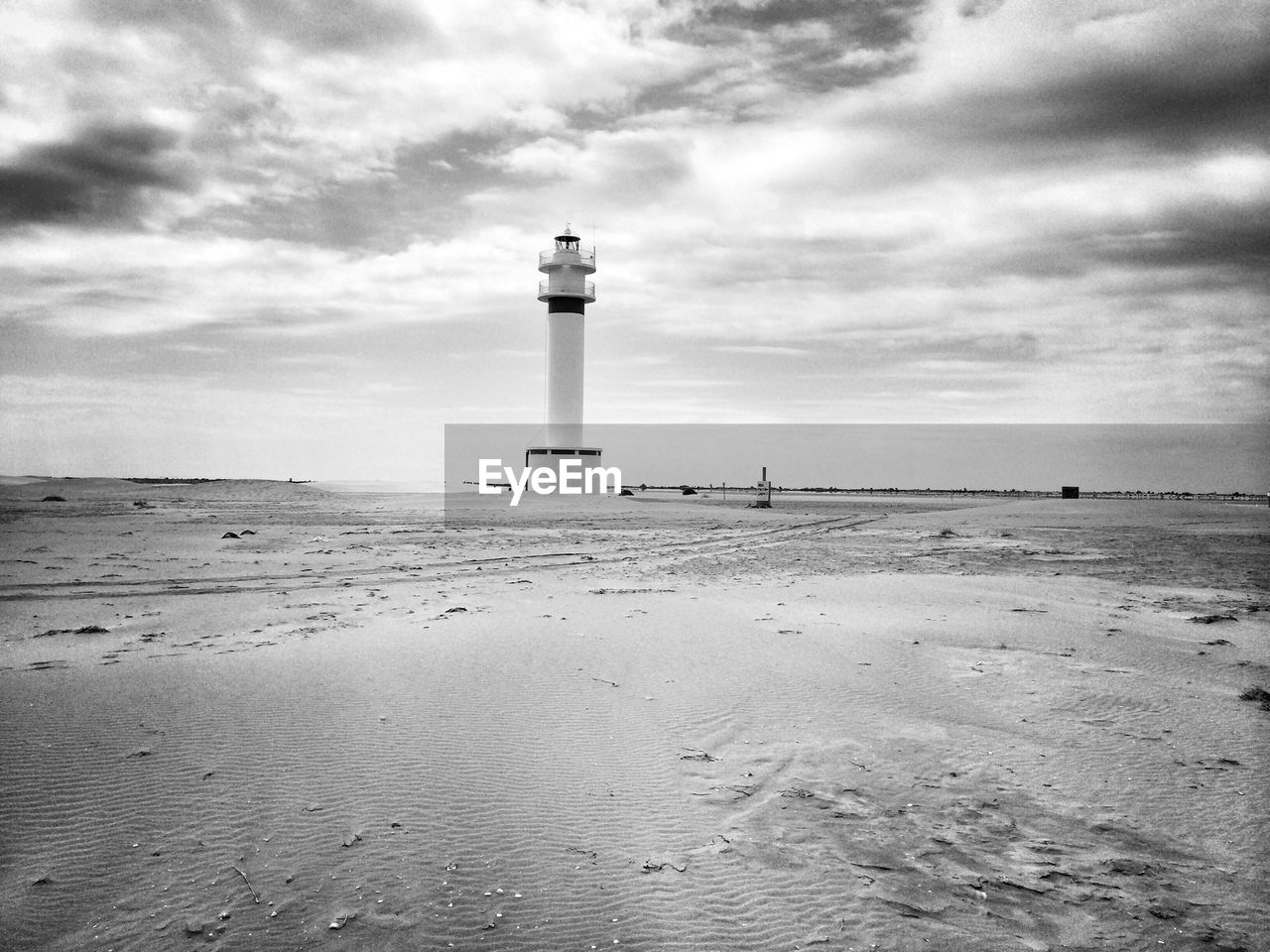 Lighthouse on beach against sky