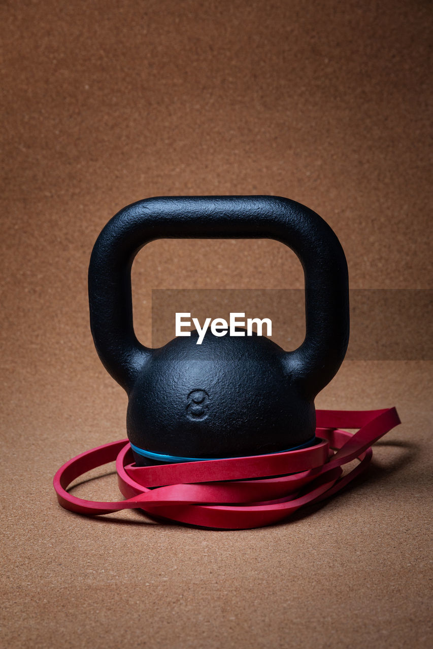 Close-up of kettlebell with rubber bands against brown background