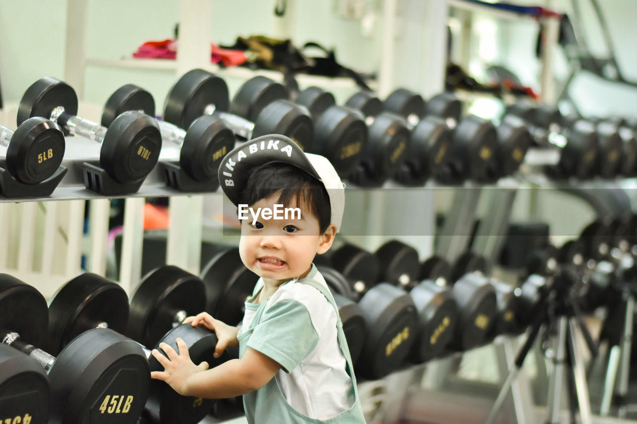 midsection of woman lifting dumbbell in gym