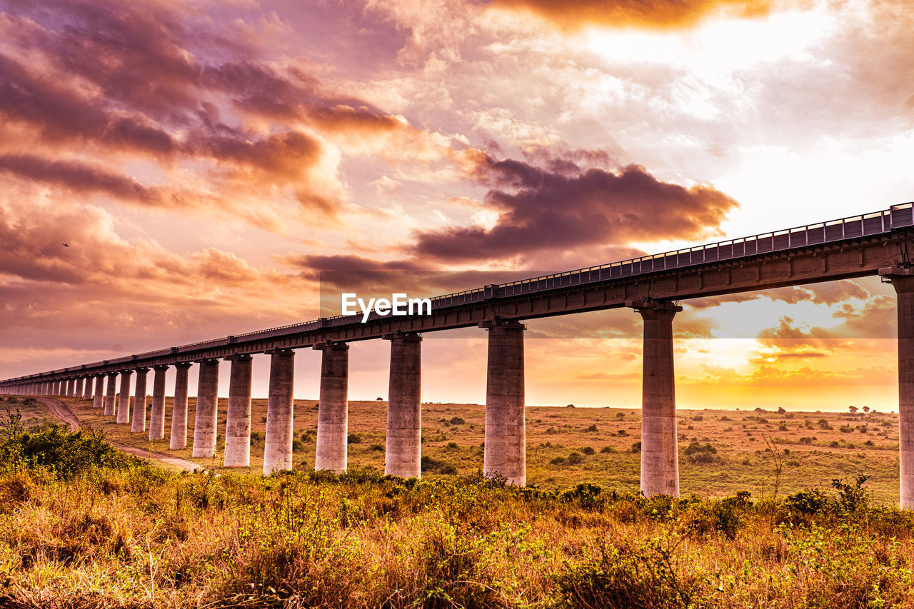 sky, sunset, cloud, architecture, bridge, built structure, nature, evening, transportation, dusk, landscape, water, dramatic sky, no people, scenics - nature, beauty in nature, environment, horizon, viaduct, land, travel destinations, sunlight, travel, outdoors, tranquility, beam bridge, rail transportation, plant, sea, grass, twilight, tranquil scene, sun, architectural column, orange color, beach, idyllic