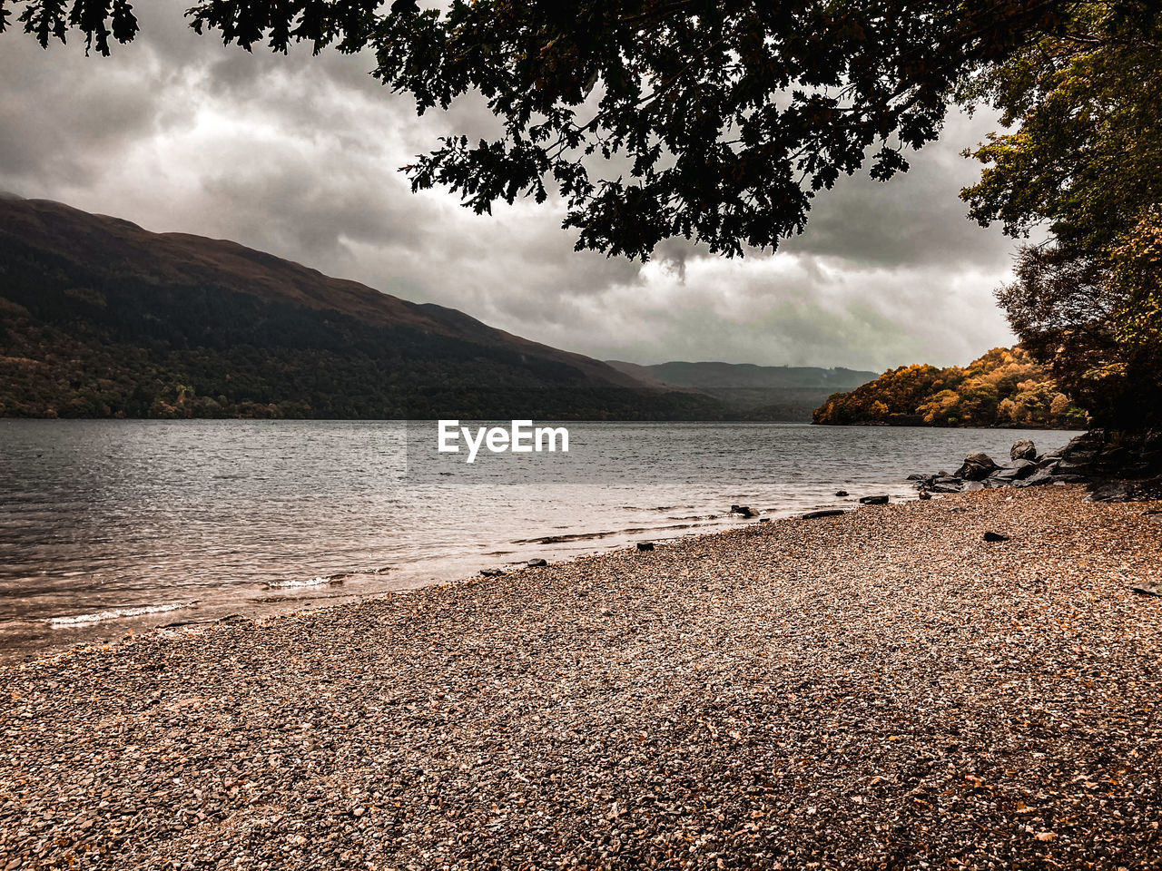 SCENIC VIEW OF LAKE BY MOUNTAIN AGAINST SKY