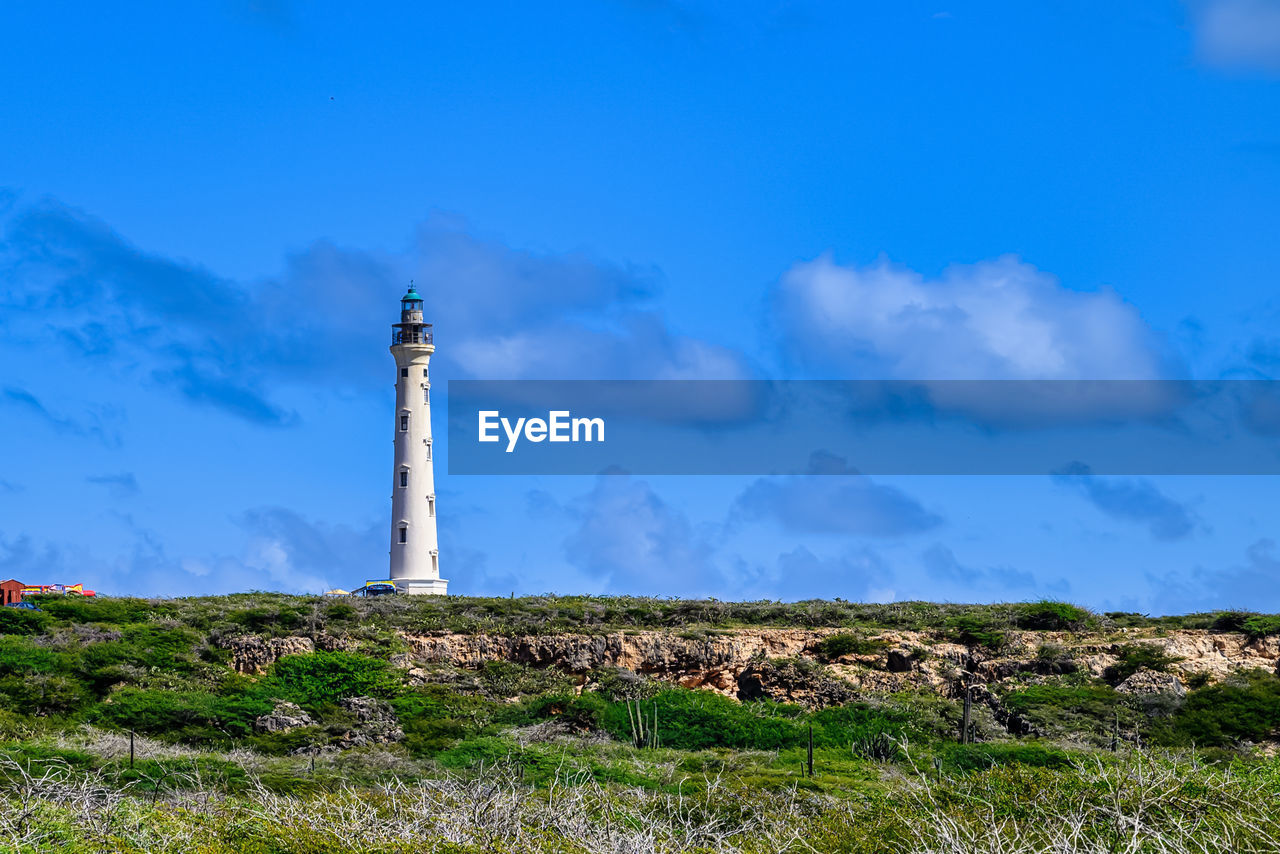 sky, tower, architecture, environment, built structure, landscape, lighthouse, nature, guidance, blue, land, building, horizon, travel destinations, building exterior, cloud, travel, hill, no people, grass, sea, scenics - nature, plant, security, outdoors, beauty in nature, protection, tourism, day, non-urban scene, history, field, copy space, coast, water, tranquility, the past, communication