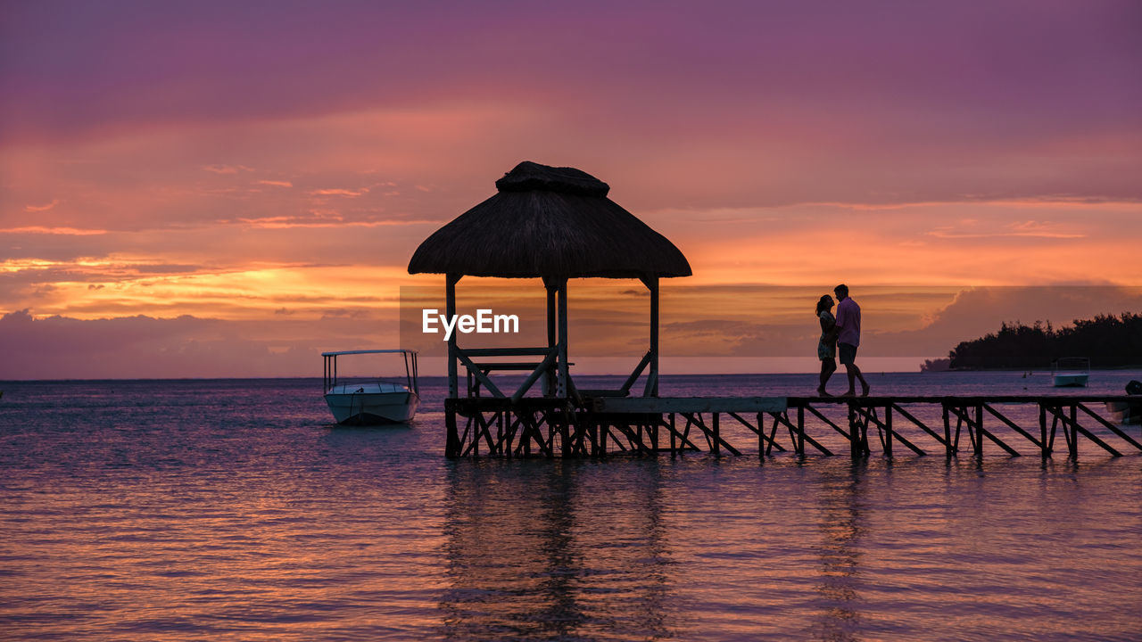 Silhouette pier over sea against sky during sunset