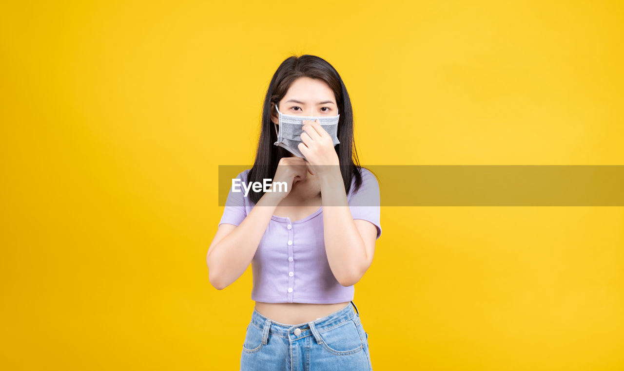 PORTRAIT OF A BEAUTIFUL YOUNG WOMAN WEARING YELLOW BACKGROUND