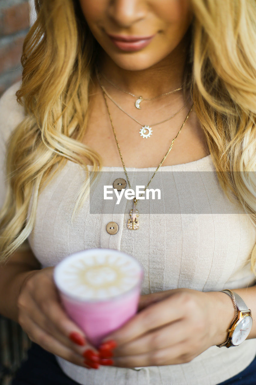 MIDSECTION OF A WOMAN HOLDING COFFEE