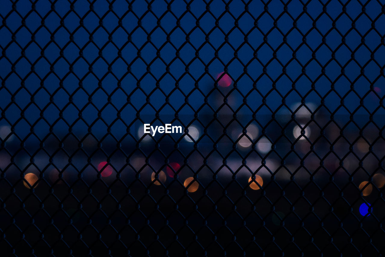 Chainlink fence against airport building at night. 