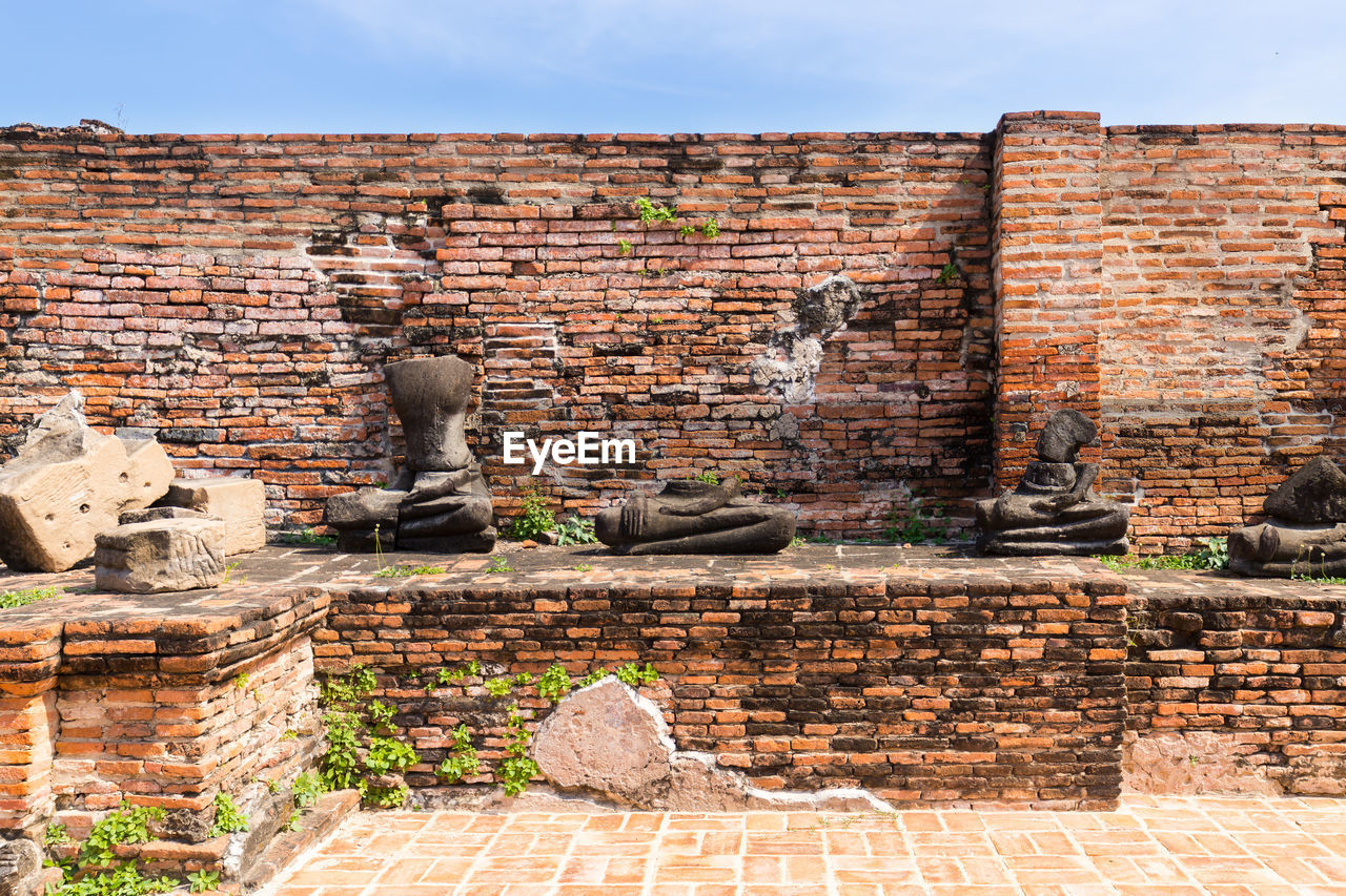 VIEW OF STATUE AGAINST BRICK WALL AND STONE