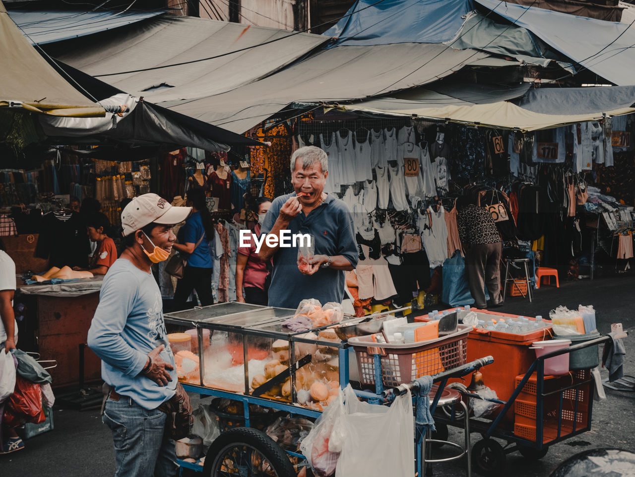 PEOPLE AT MARKET STALL IN CITY