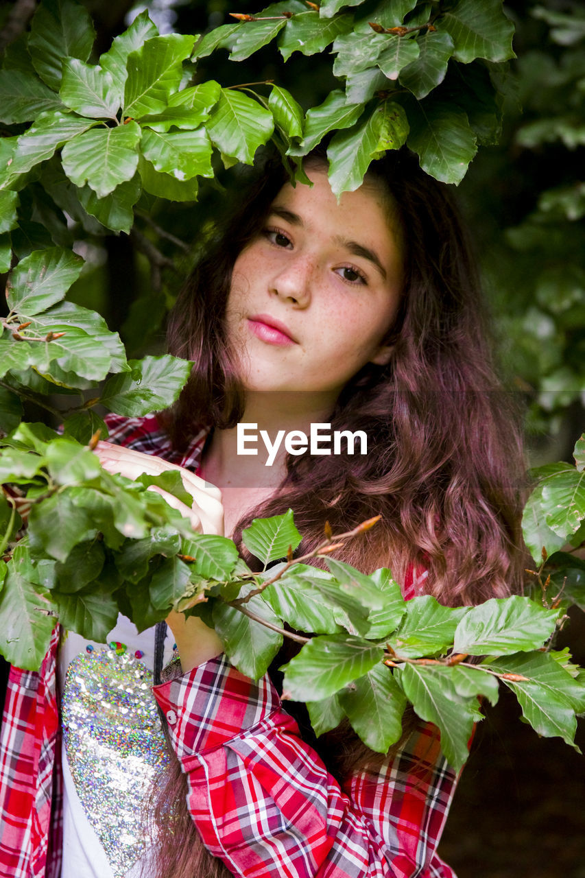 Portrait of smiling teenage girl standing by plants