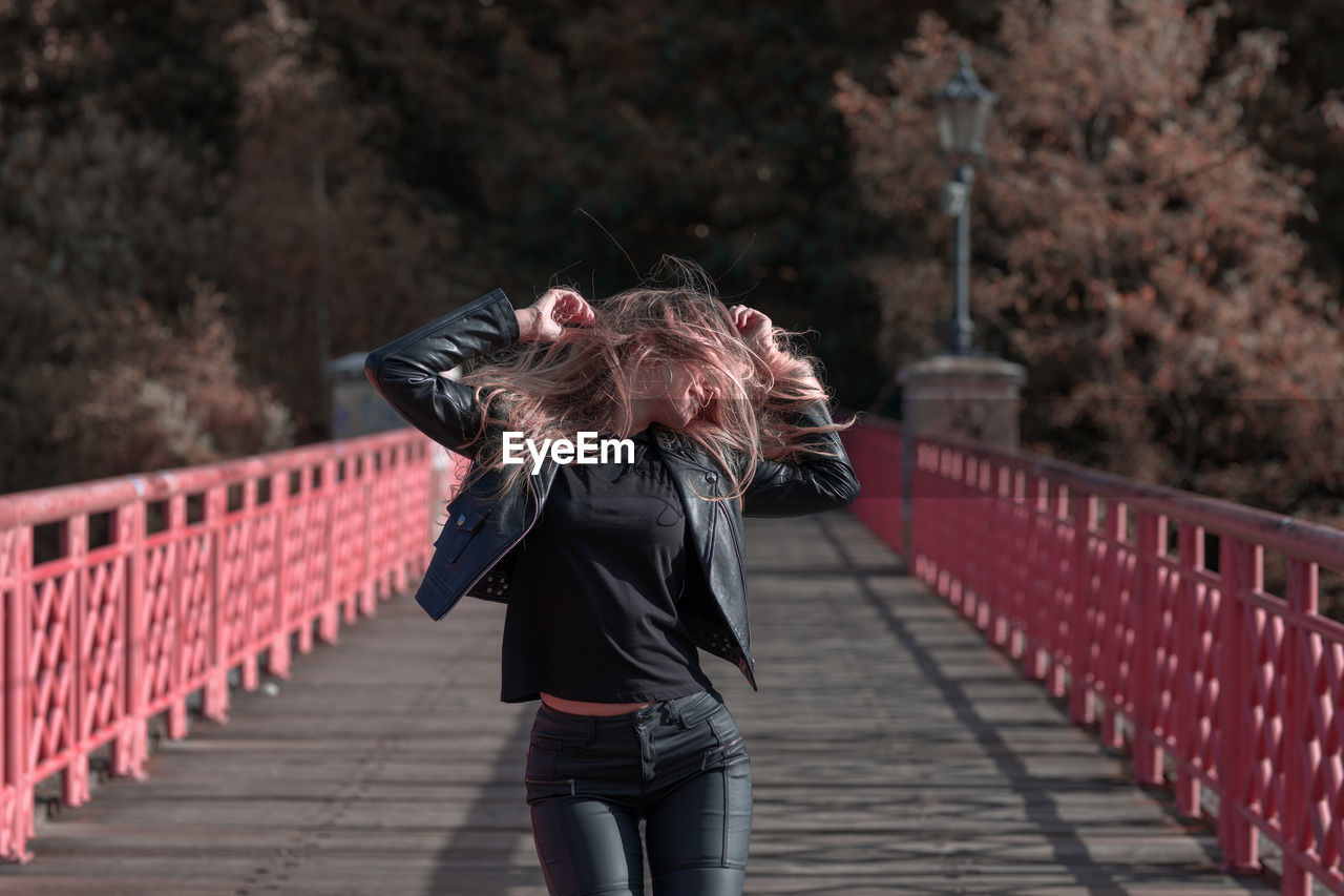 Young woman with blond hair standing on footbridge