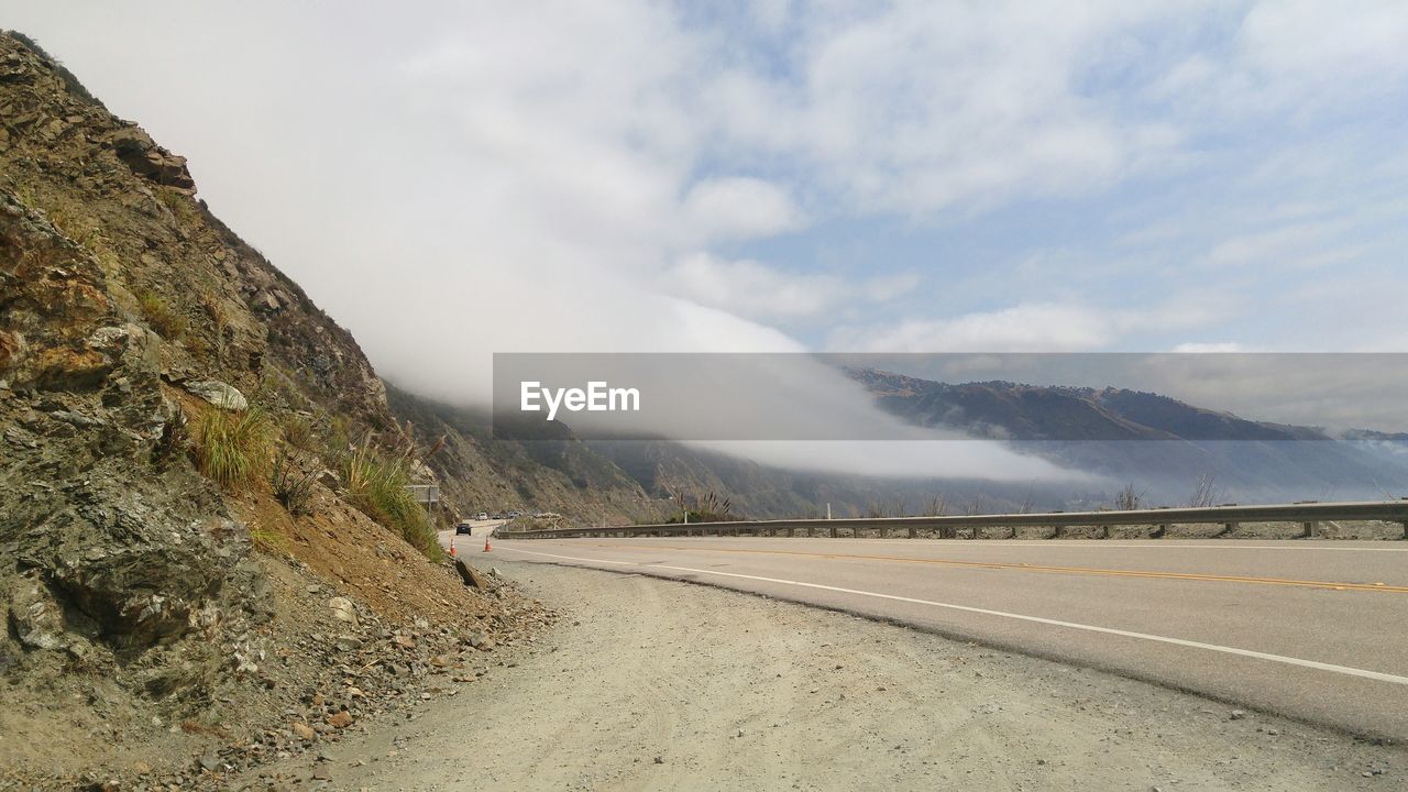 Empty road by mountains against sky