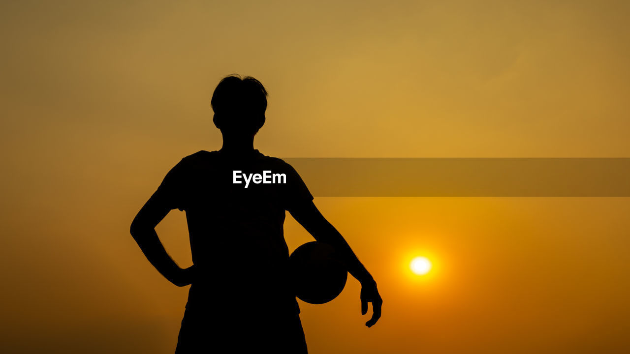 SILHOUETTE WOMAN STANDING AGAINST ORANGE SKY